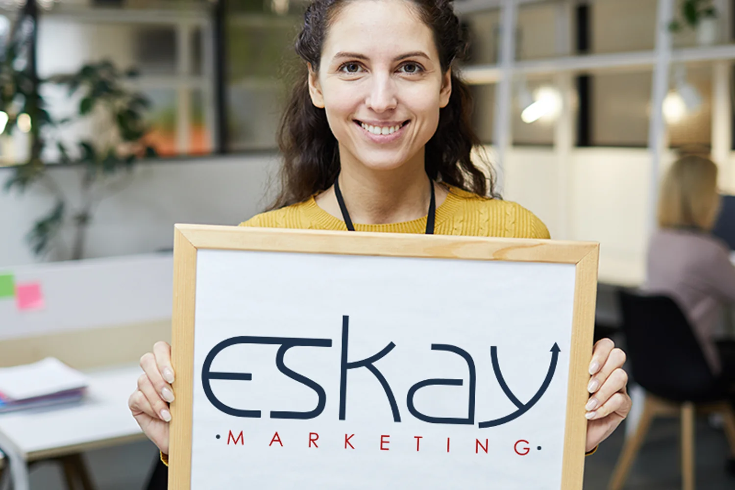 An Eskay Marketing team member holding the company sign at the agency's Fort Worth, Texas office