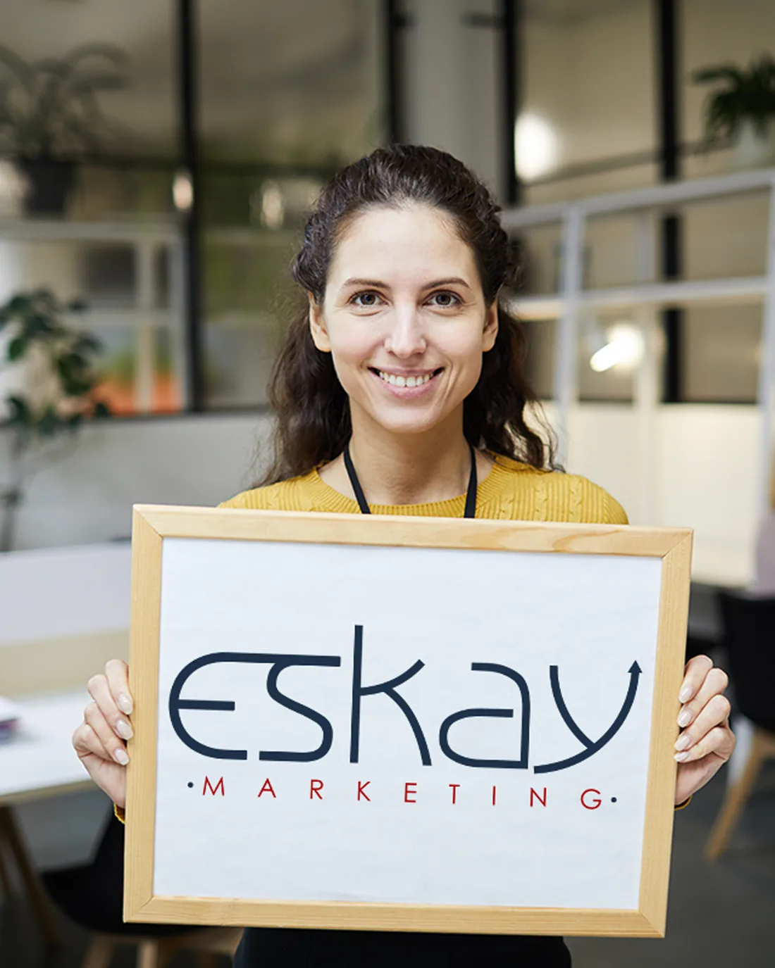 An Eskay Marketing team member holding the company sign at the agency's Fort Worth, Texas office